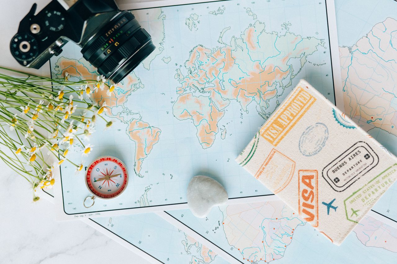 how-it-works Flat lay of travel essentials: maps, camera, compass, and travel journal for planning adventures.